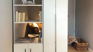 Una camera da letto con un'armadio bianco, un letto con copripiumino bianco e un cesto di vimini sul pavimento.