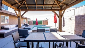 Eine Außenpatio mit Pool, Korbmöbeln und einem überdachten Bereich mit Metalldach.