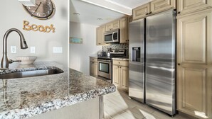 Eine Küche mit Granit Arbeitsplatten, Edelstahlgeräten und Holzschränken.