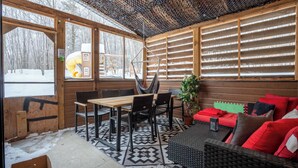 Interior de madera con zona de comedor, un sofá y un ventanal grande.