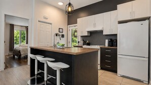 Una cocina moderna con una isla central, taburetes de bar y un refrigerador.