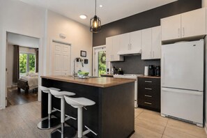 Una cocina moderna con una isla central, taburetes de bar y un refrigerador.