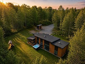 A modern two-story house with a swimming pool, surrounded by a forested area.