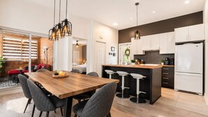 Una cocina moderna con una mesa de comedor de madera, taburetes de bar y un refrigerador.