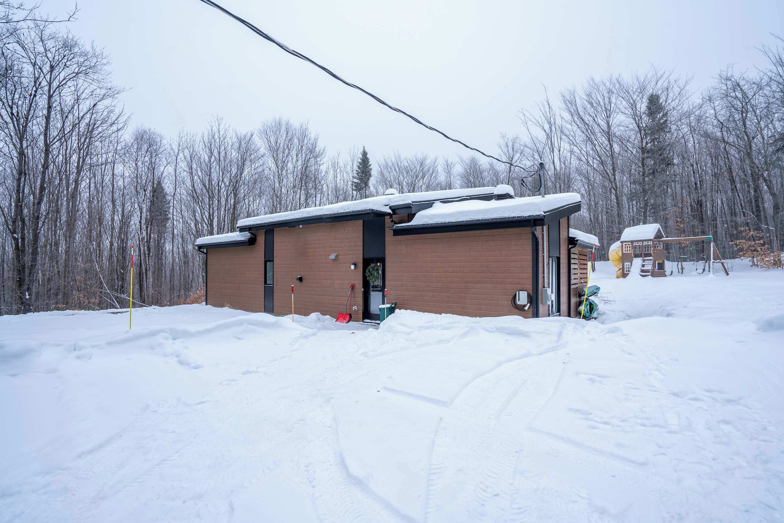 Un bâtiment enneigé, avec une façade en briques et une porte ouverte sur le côté droit.