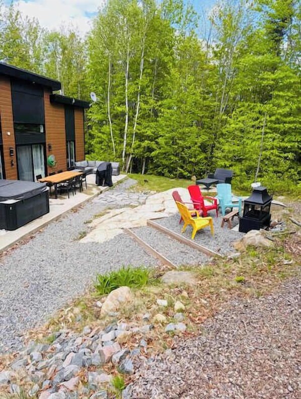 An outdoor patio area with a wooden deck, outdoor seating, and a grill.