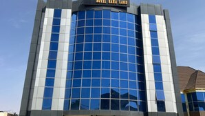 A modern hotel building with a reflective glass facade and a sign reading "HOTEL SAHA LAND".