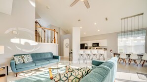 A spacious living area with a blue sofa, a coffee table, and a staircase leading to an upper floor. - 3 Mi to Disney: Family-friendly Home! (Kissimmee)