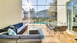 An outdoor patio with a pool, wicker furniture, and a glass table. - 3 Mi to Disney: Family-friendly Home! (Kissimmee)
