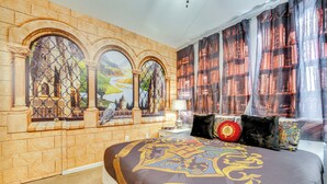 A bedroom with a stone wall, a mural, a large bed with a Hogwarts-themed duvet, and a bookshelf. - 3 Mi to Disney: Family-friendly Home! (Kissimmee)