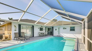 A swimming pool with a glass enclosure, lounge chairs, and a table. - 4 Mi to Lakes Park: Family Home in Fort Myers! (Fort Myers)