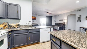 A modern kitchen with dark cabinets, granite countertops, and a dishwasher.