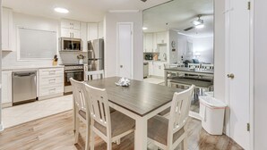 A modern kitchen with white cabinetry, a wooden dining table, and a ceiling fan. - 'wright by the Beach': Hilton Head Condo w/ Perks (Hilton Head Island)