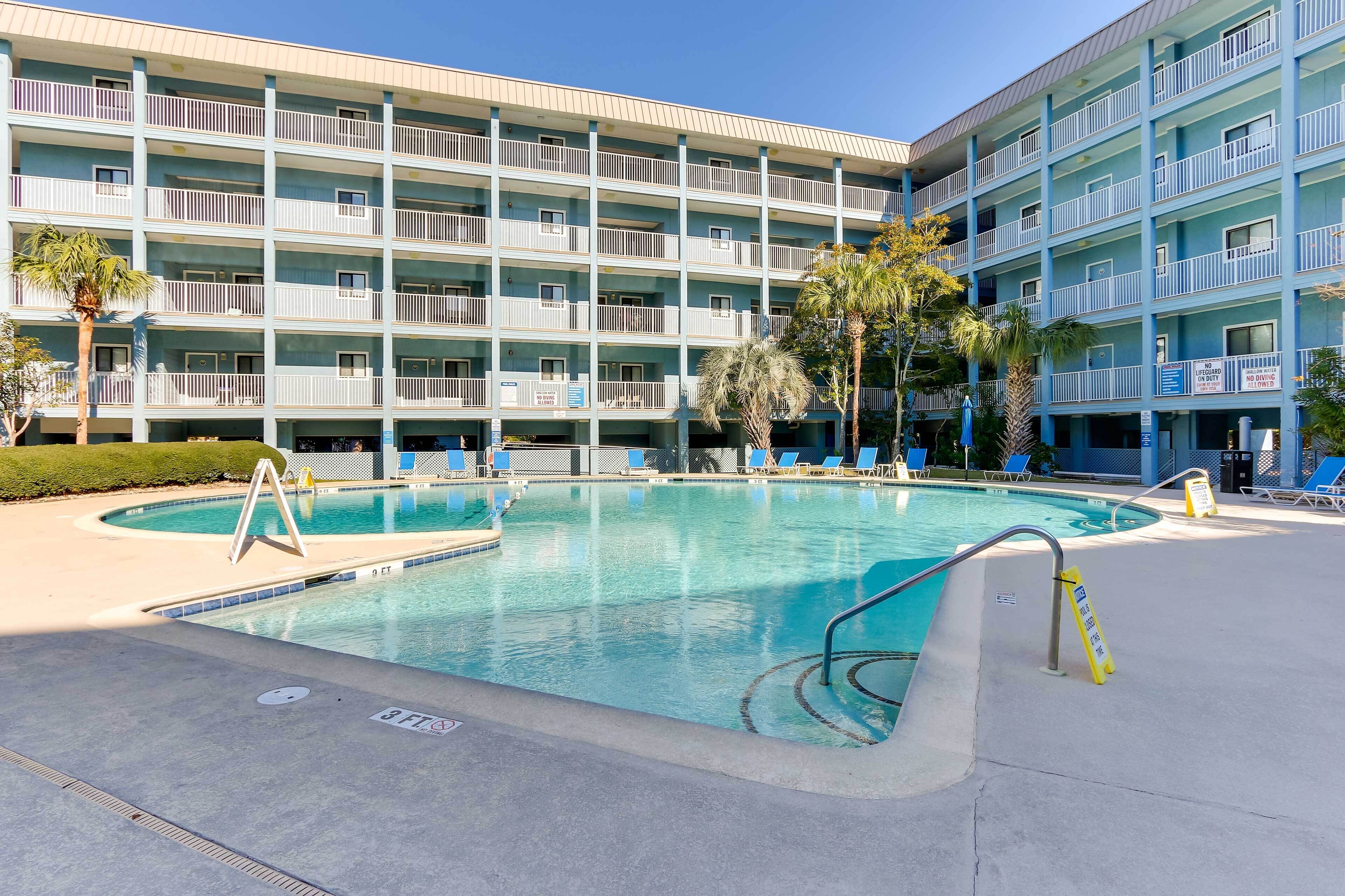Un hotel con piscina, varios balcones y un cielo azul despejado.