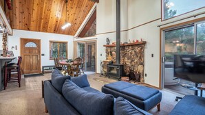 A cozy living room with a fireplace, a dining area, and a large TV.