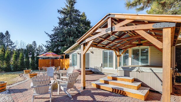 A covered patio area with Adirondack chairs, a wooden deck, and a hot tub. - Bend Golf & Country Club Vacation Home (Bend)