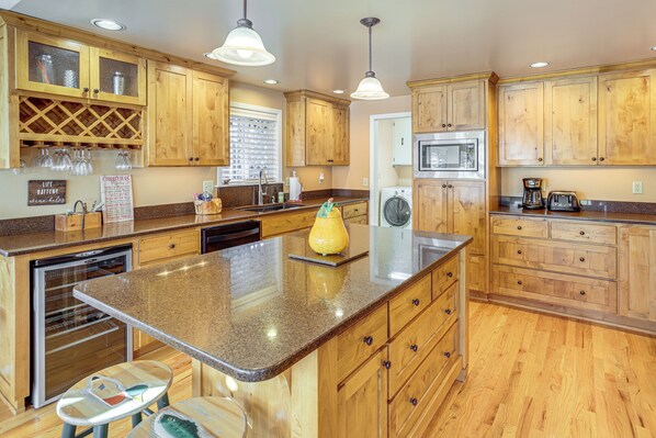 A kitchen with wooden cabinets, granite countertops, a dishwasher, a microwave, and a coffee maker. - Bend Golf & Country Club Vacation Home (Bend)