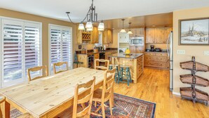 A spacious kitchen with wooden cabinets, a large island, and a dining area with a wooden table and chairs. - Bend Golf & Country Club Vacation Home (Bend)