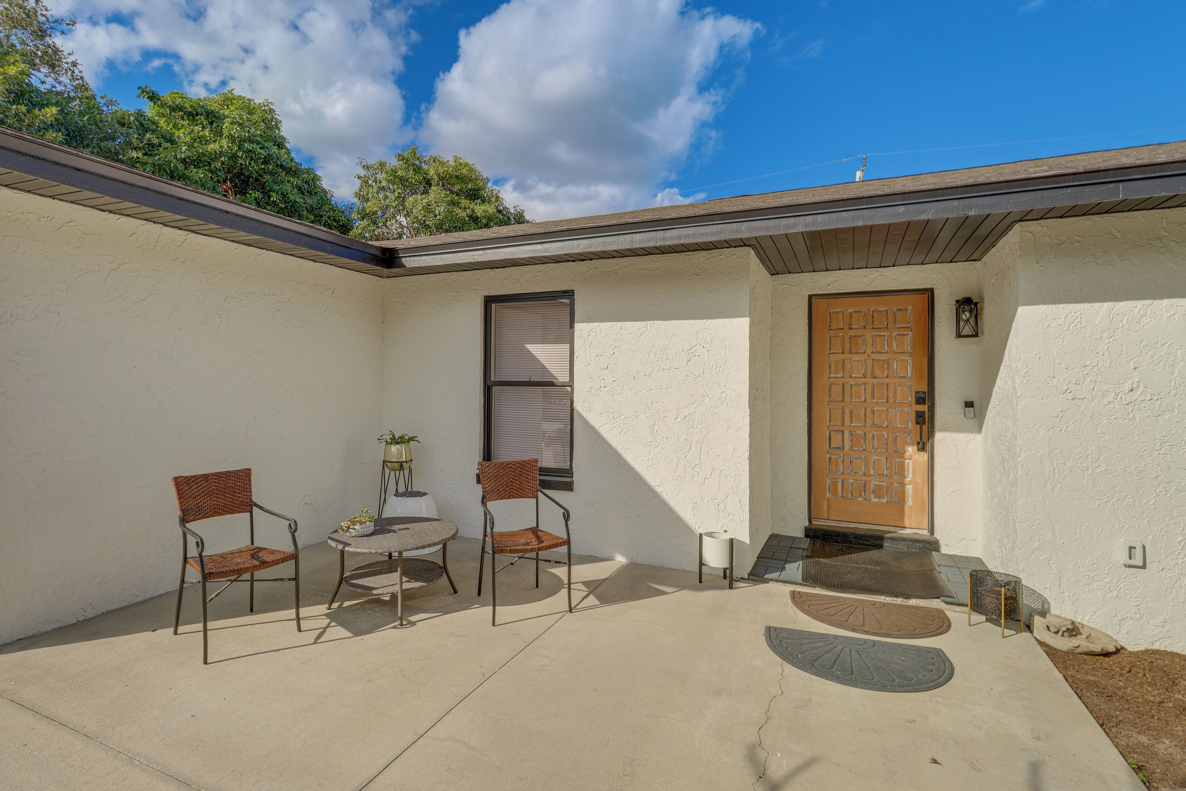 A patio with two chairs and a small table, a door, and a window.