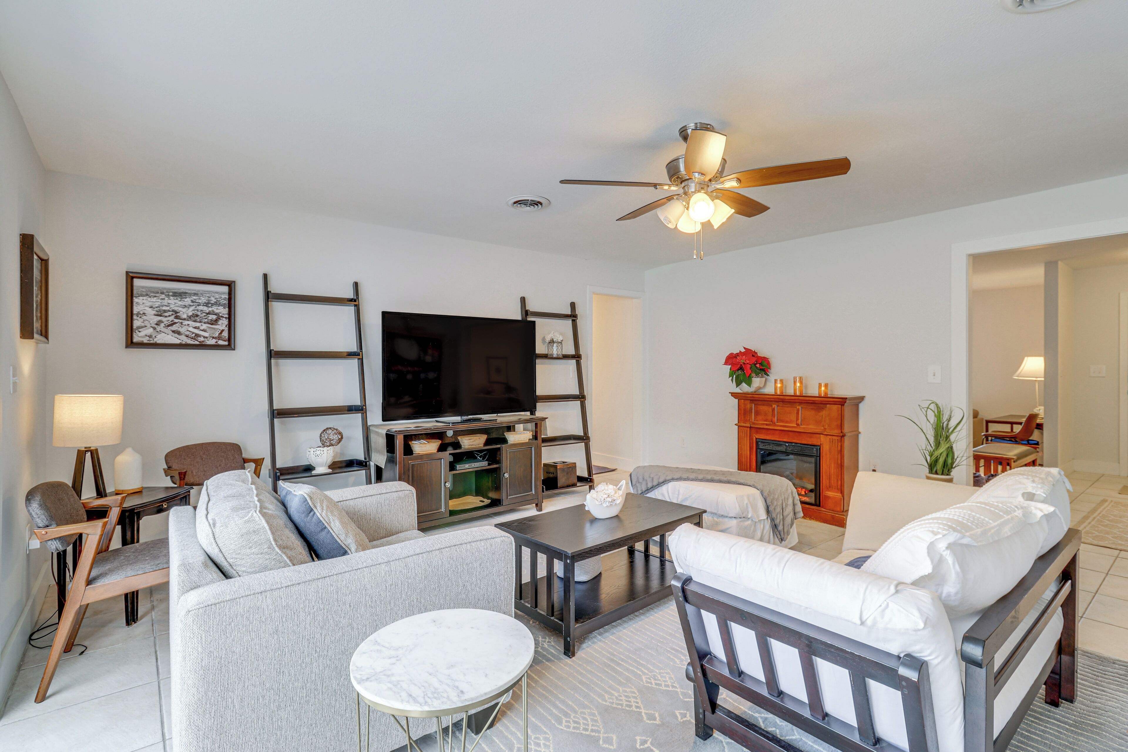 A modern living room with a sofa, armchairs, a coffee table, a TV, and a fireplace.
