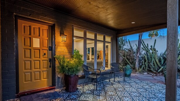 Un patio couvert doté d’un sol à motifs, d’une porte en bois et de sièges d’extérieur.