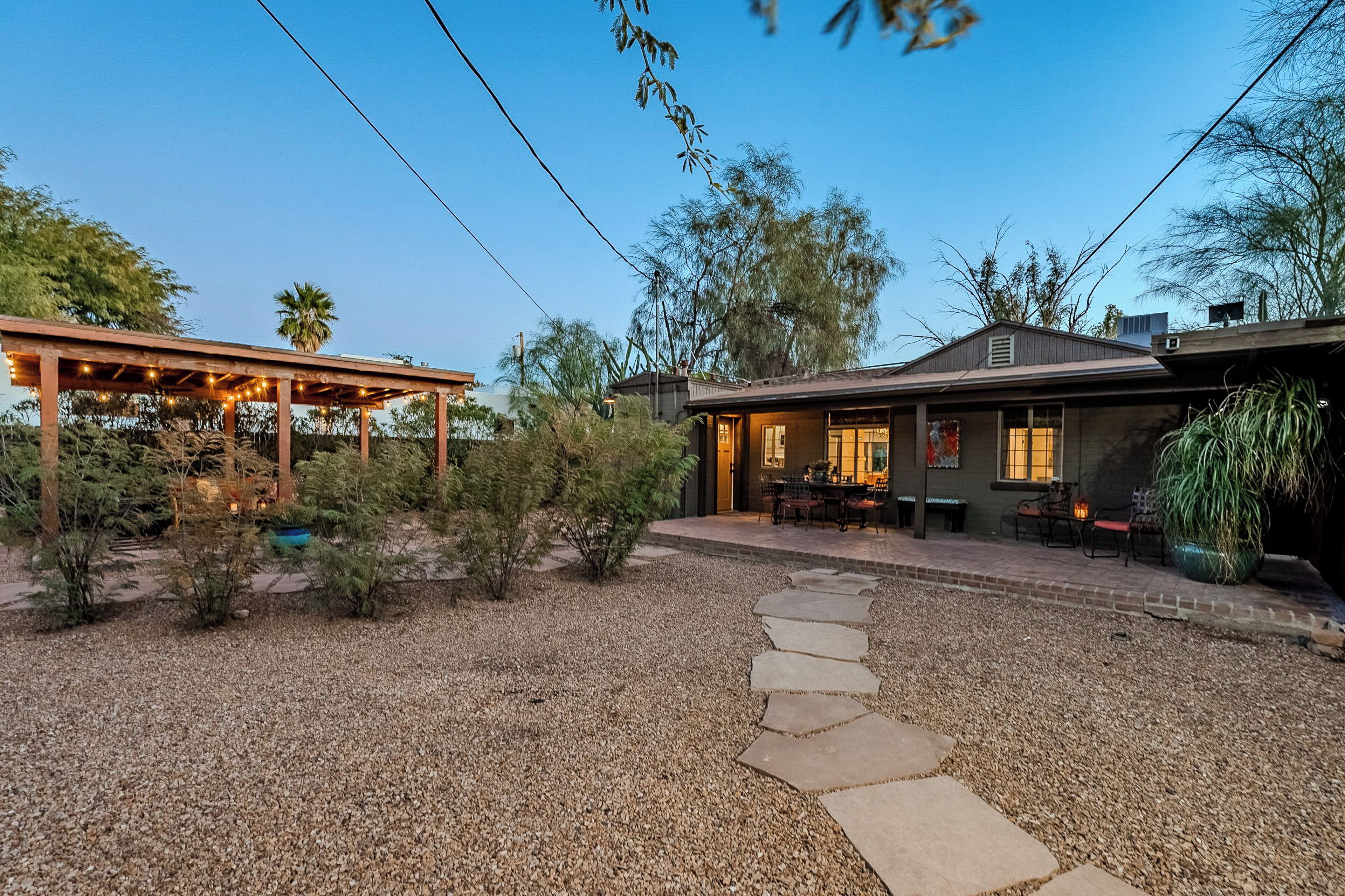 A house with a covered patio, a gravel driveway, and a stone pathway leading to the entrance.