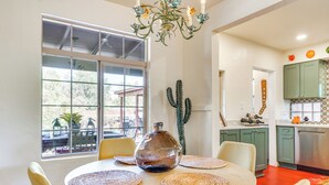 Un coin repas avec une table ronde, des chaises, un vase en verre et un cactus.