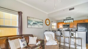 A living room with a brown leather sofa, a wicker chair, and a coffee table with a potted orchid. - Short Walk to Bay & Ocean: Treasure Island Condo (Treasure Island)