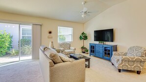 A living room with a sofa, armchairs, a coffee table, a TV, and a blue cabinet. - Golf, Shop & Unwind: Lovely Home in The Villages! (Wildwood)