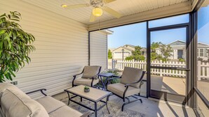A covered patio with a ceiling fan, two chairs, a small table, and a potted plant. - Golf, Shop & Unwind: Lovely Home in The Villages! (Wildwood)