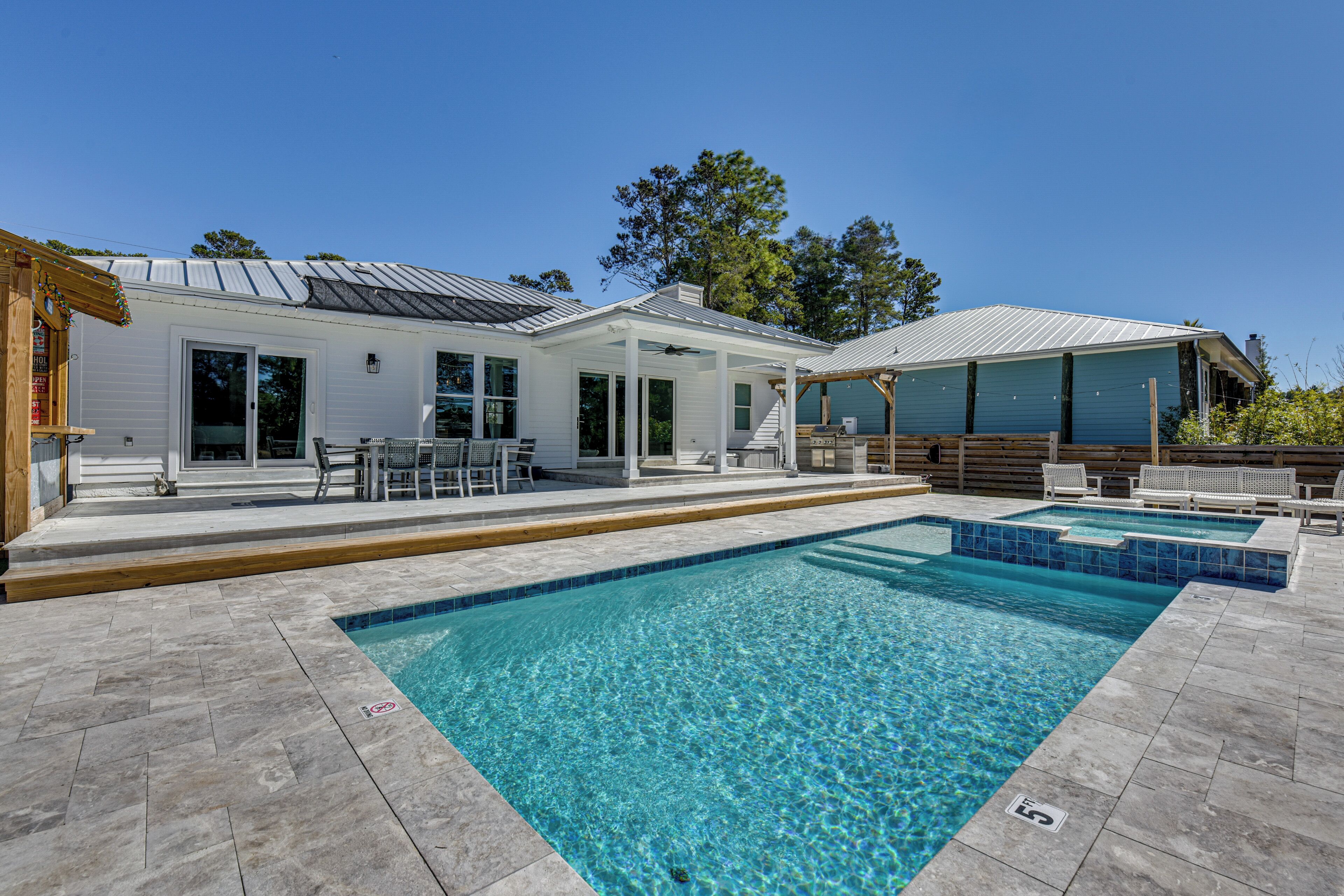 A modern house with a swimming pool, outdoor seating, and a covered patio area.