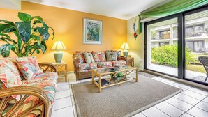Ein Wohnzimmer mit einer Couch, einem Couchtisch und einer großen Pflanze.