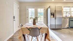 A dining area with a table set for four, a refrigerator, and a window with a view of greenery. - 4 Mi to Dtwn: Home w/ Fire Pit in Greenville (Greenville)