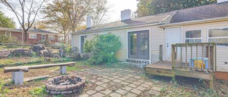 A residential backyard with a fire pit, a wooden deck, and a brick patio.