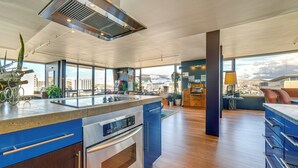 Une cuisine moderne dotée d’un grand îlot central, d’appareils électroménagers en acier inoxydable et offrant une vue sur la ville.