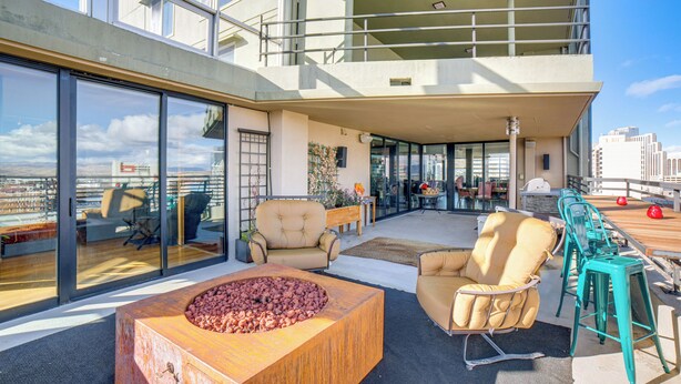 Une terrasse sur le toit dotée d’un foyer, d’un espace salon et offrant une vue sur le paysage urbain.