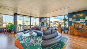 Un salon spacieux avec une grande fenêtre, un canapé en cuir, une table basse et une vue sur la ville.