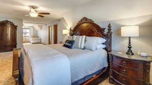 Ein Schlafzimmer mit einem großen Bett, einem Holzkopfteil, einem Nachttisch und einem Deckenventilator.