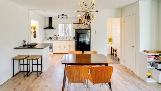 A modern kitchen with a central island, wooden stools, a dining table with chairs, and a unique chandelier. - Mtn Views + On-site Hiking Trails: Catskills Cabin (Round Top)