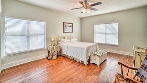 A bedroom with a bed, a nightstand, a chair, and a ceiling fan. - 4 Miles to Lake Jacksboro: Cozy Texas Cottage (Jacksboro)