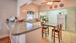 A kitchen with a granite countertop, wooden chairs, a ceiling fan, and a refrigerator. - 4 Miles to Lake Jacksboro: Cozy Texas Cottage (Jacksboro)