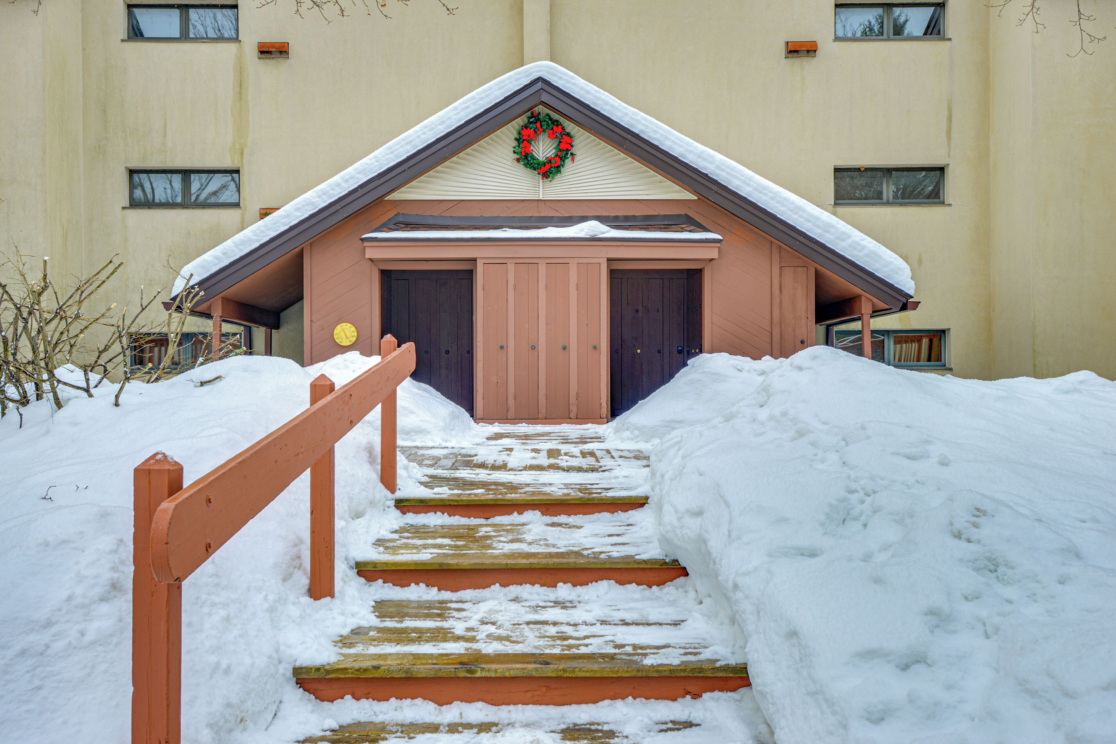 A building with a snow-covered entrance and a wooden staircase leading up to it.