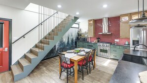 A modern kitchen with a dining area, a staircase, and a red door. - 5 Mi to Wec: Pet-friendly Home in Wilmington (Wilmington)