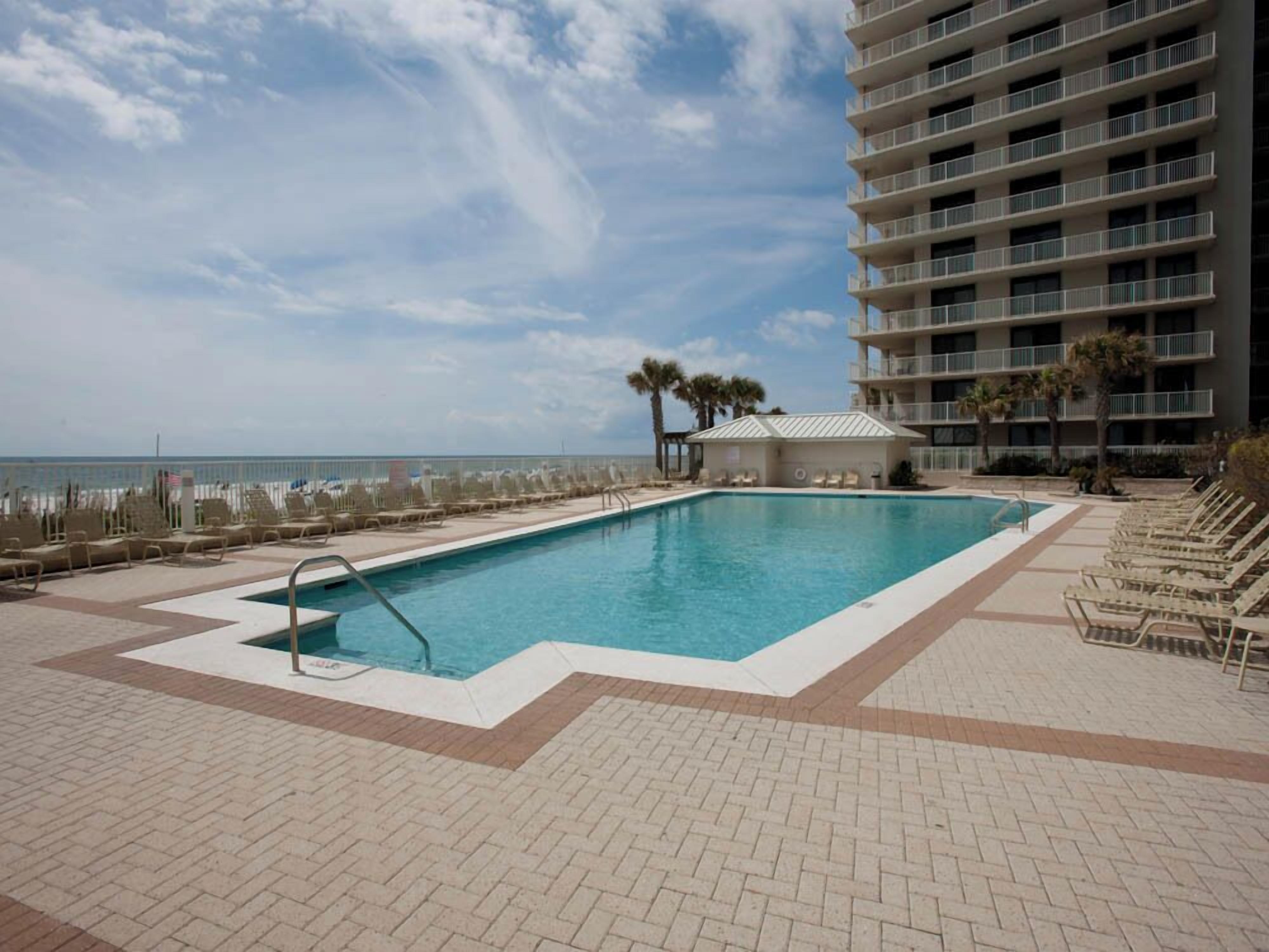 A swimming pool with lounge chairs and a view of the ocean.