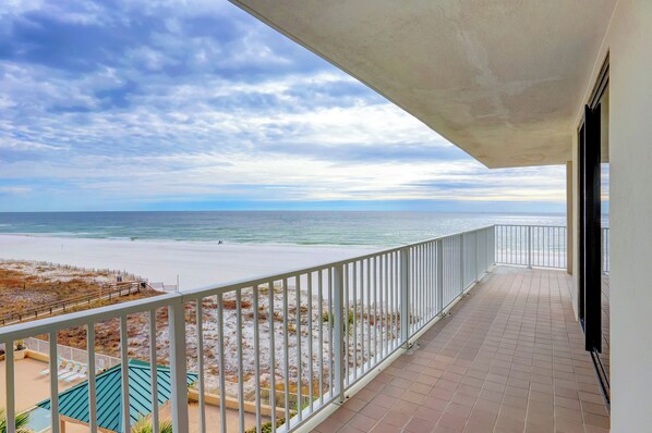 A balcony with a view of the beach and ocean.