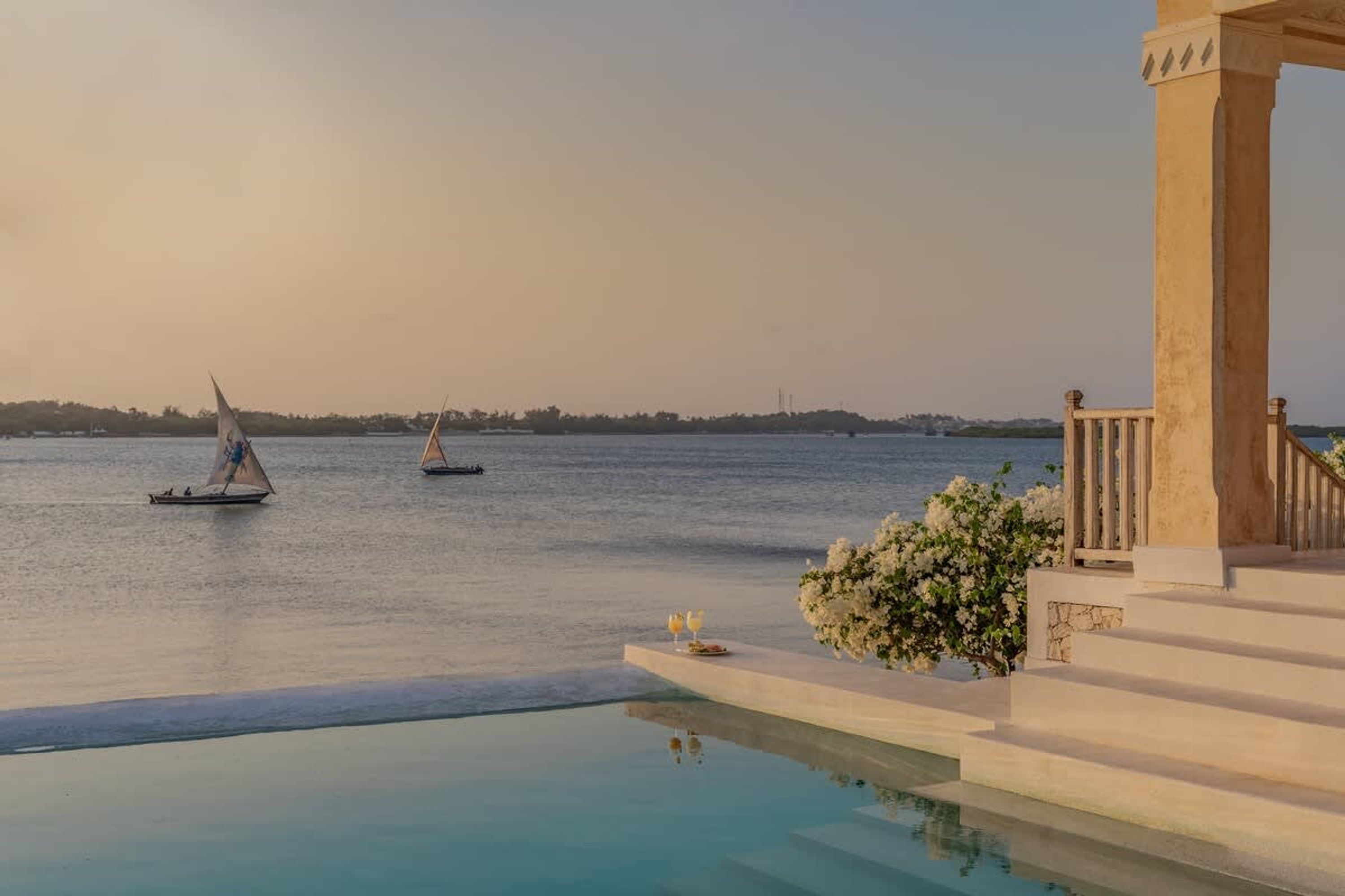 A serene pool area with a clear view of the sea and boats.