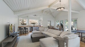 A spacious living area with a large sectional sofa, a kitchen with bar seating, and a dining area with natural light. - Hot Tub | Sauna | Game Room!  5 Acres - 2 miles from Downtown (Durango)