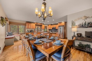 Una cocina amplia con armarios de madera, una isla central y un comedor con mesa y sillas de madera.