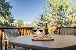 A table with a bottle of wine, two glasses, and a plate of snacks.
