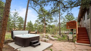 A hot tub with steps, outdoor seating, and a staircase leading to a wooden deck.